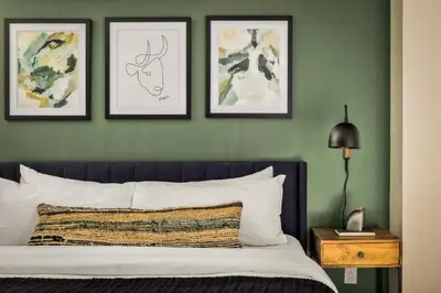 a bedroom with green walls with a bed and three framed pictures at Urban Gallery Loft - King Bed - Larimer Square in Denver