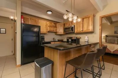 a kitchen with wooden cabinets and a black refrigerator at Lodge at Lake Dillon Condo: Great Year-Round Location in Dillon