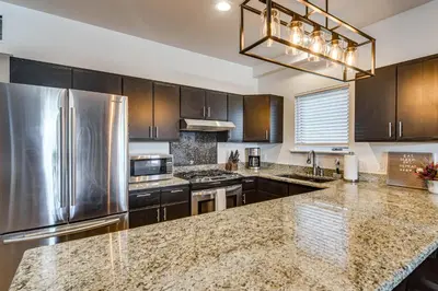 a kitchen with stainless steel appliances and brown cabinets at Downtown Winter Park Condo with Free Bus to Ski Base in Winter Park