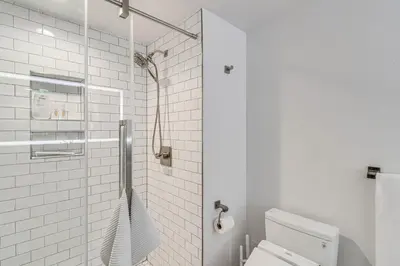 a white bathroom with a toilet and a shower at Downtown Winter Park Condo with Free Bus to Ski Base in Winter Park