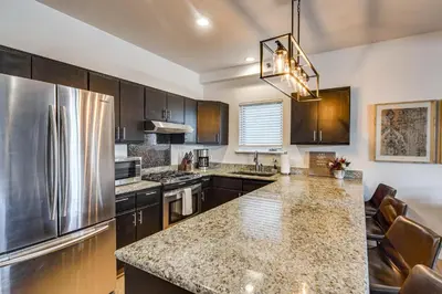 a kitchen with wooden cabinets and a stainless steel refrigerator at Downtown Winter Park Condo with Free Bus to Ski Base in Winter Park