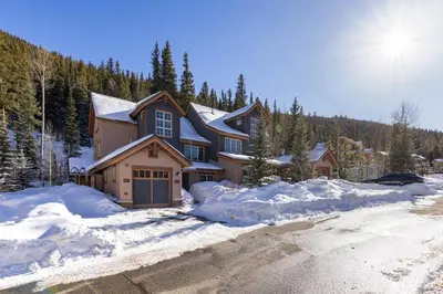 a house in the snow with the sun behind it at 6533 Settlers Creek townhouse in Keystone