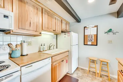 a kitchen with wooden cabinets and a white refrigerator at Cozy Estes Park Condo with Balcony and Fireplace! in Estes Park