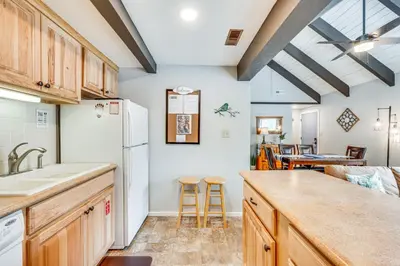 a kitchen with a white refrigerator and wooden cabinets at Cozy Estes Park Condo with Balcony and Fireplace! in Estes Park