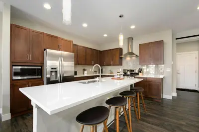 a kitchen with a white counter top and wooden cabinets at Exquisite Home by Old Town - Steps from Poudre Trail in Fort Collins