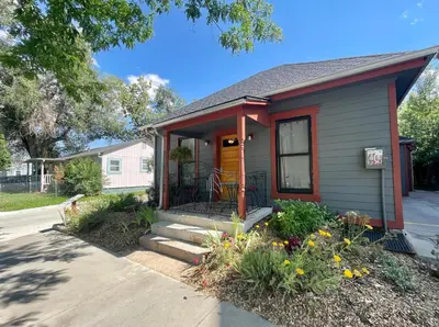 a small house with a yellow door and flowers at The Hattie House in Old Town - Walk Everywhere! in Fort Collins
