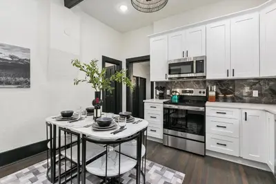 a kitchen with white cabinets and a small table at Old Town Retreat with Hot Tub - Steps from CSU! in Fort Collins