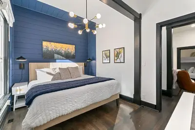 a blue bedroom with a bed and a mirror at Old Town Retreat with Hot Tub - Steps from CSU! in Fort Collins