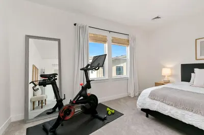 a bedroom with a bed and a exercise bike and a mirror at Coastal Chic Home near New Belgium & Old Town FC in Fort Collins