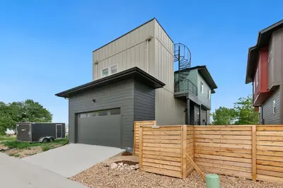 a building with a garage next to a fence at Coastal Chic Home near New Belgium & Old Town FC in Fort Collins