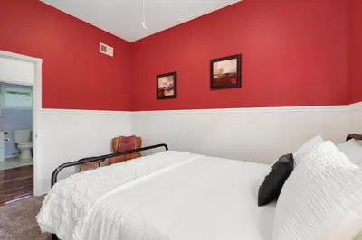 a bedroom with red walls and a white bed at The Magnolia House in Old Town - Private Hot Tub in Fort Collins