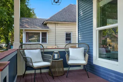 a porch with two chairs and a table with a lantern at The Magnolia House in Old Town - Private Hot Tub in Fort Collins