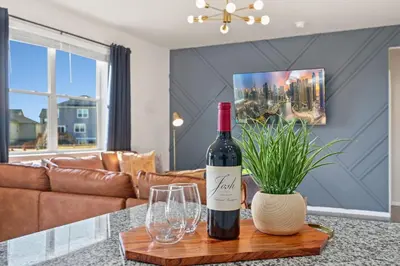 a bottle of wine and glasses on a table in a living room at NEW! Family-friendly Home with Pool Table, King Beds in Windsor