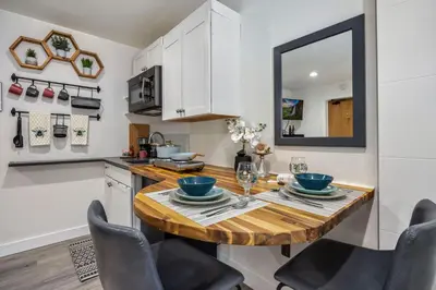 a kitchen with a wooden table and a mirror at The Fox Den in Old Town! Pool, Sauna & Game Room in Fort Collins