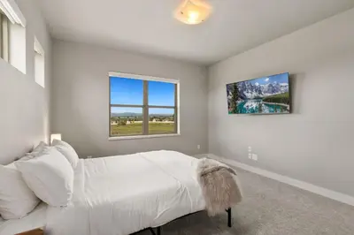 a bedroom with a white bed and two windows at Luxury Home with Spectacular Rocky Mountain Views! in Eaton