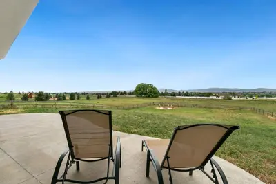 two chairs sitting on a patio with a view of a field at Luxury Home with Spectacular Rocky Mountain Views! in Eaton