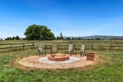 four chairs around a fire pit in a field at Luxury Home with Spectacular Rocky Mountain Views! in Eaton
