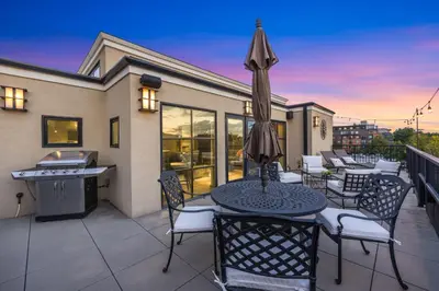 a patio with a table and chairs and an umbrella at Penthouse with Mountain Views in the Heart of Old Town in Fort Collins