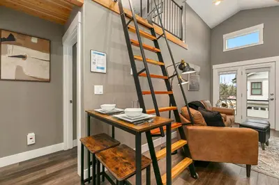 a spiral staircase in a living room with a table at Luxury Living - Walk to Poudre Trail and Old Town! in Fort Collins