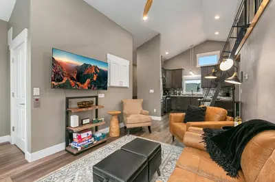 a living room with a couch and a tv on a wall at Luxury Living - Walk to Poudre Trail and Old Town! in Fort Collins