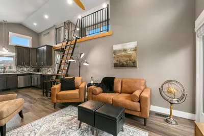 a living room with furniture and a spiral staircase at Luxury Living - Walk to Poudre Trail and Old Town! in Fort Collins