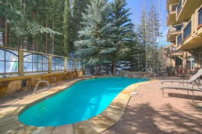 a swimming pool in front of a building with trees at 3Br Ski-in Ski-out-On Mountain-Lone Eagle 3053 condo in Dillon