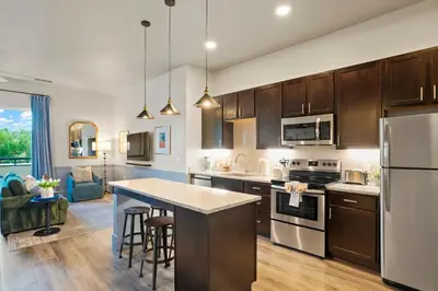 a kitchen with wooden cabinets and a kitchen island with bar stools at Golden Condo Patio with MTN Views Walk to DT Golden and School of Mines in Golden