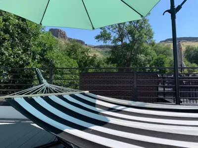 a hammock with an umbrella on top of a roof at Golden Rooftop w Mountain Views - Walk to DT Golden School of Mines Close to Red Rocks in Golden