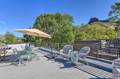 a deck with chairs and a table and an umbrella at Golden Rooftop w Mountain Views - Walk to DT Golden School of Mines Close to Red Rocks in Golden