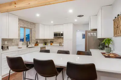 a kitchen with white cabinets and a table and chairs at One of a Kind Home with HOT TUB Pool Table and Fire Pit 4 Miles to DT in Denver