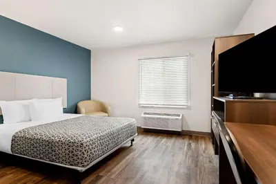 a bedroom with a bed and a flat screen tv at WoodSpring Suites Denver Commerce City in Commerce City