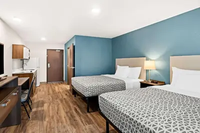 a hotel room with two beds and a television at WoodSpring Suites Denver Commerce City in Commerce City