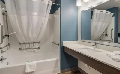 a bathroom with a tub and a sink and a mirror at WoodSpring Suites Denver Commerce City in Commerce City