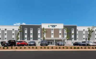 a large building with cars parked in a parking lot at WoodSpring Suites Denver Commerce City in Commerce City