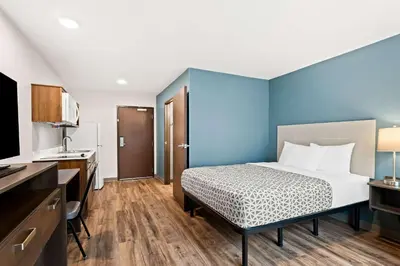 a bedroom with a bed and a blue wall at WoodSpring Suites Denver Commerce City in Commerce City