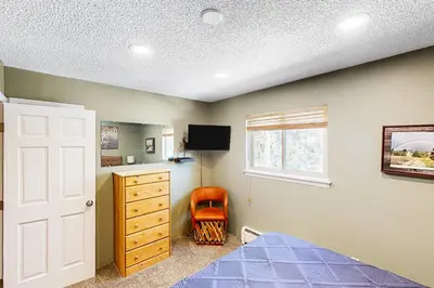 a bedroom with a bed and a dresser and a window at Hi Country Haus Haven in Winter Park