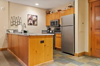 a kitchen with wooden cabinets and a stainless steel refrigerator at River Run 2BD Condo Walk to Ski and Lift in Keystone