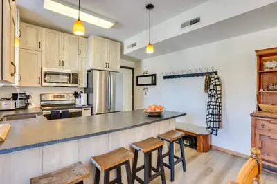 a kitchen with wooden cabinets and a counter with stools at Fantastic Fraser Condo Year-Round Family Getaway in Fraser