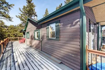 a cabin with a wooden deck with a red chair on it at Skipper's Cabin in Pine
