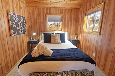 a bedroom with a large bed with wooden walls at Skipper's Cabin in Pine