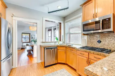 a kitchen with wooden cabinets and stainless steel appliances at 4 Mi to Downtown Denver Washington Park Hideaway! in Denver
