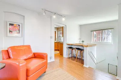 a living room with an orange chair and a kitchen at 4 Mi to Downtown Denver Washington Park Hideaway! in Denver
