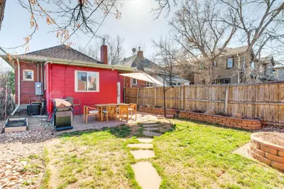 a backyard with a red house and a wooden fence at 4 Mi to Downtown Denver Washington Park Hideaway! in Denver