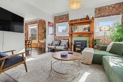 a living room with a green couch and a fireplace at 5-Bedroom Victorian Home Private Yard Sleeps 10 in Denver
