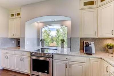 a kitchen with white cabinets and a sink and a window at Stunning Golf Course View in Denver in Denver