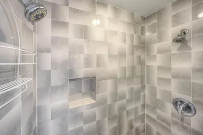 a bathroom with a tiled shower with two faucets at River Glen #106C in Frisco