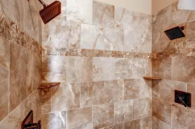 a bathroom with a large shower with brown tiles at Boulevard Bend P2 in Frisco