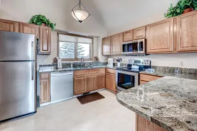 a kitchen with wooden cabinets and a stainless steel refrigerator at Pitkin Townhome 704 in Frisco
