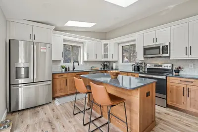 a kitchen with white cabinets and a island with bar stools at Whispering Pines-Hot tub Getaway in Bailey