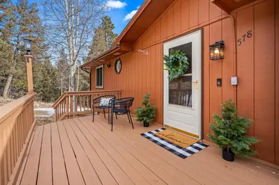 a wooden deck with two chairs on a house at Whispering Pines-Hot tub Getaway in Bailey